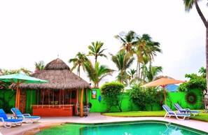 Relax by the pool surrounded by lounge chairs and umbrellas, with a bar and restaurant nearby.