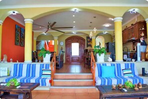 Classic design meets comfort in this elegant space with a central staircase, seating area, and potted plants.