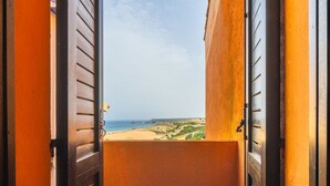 Un balcón con vista a la playa y un paisaje lejano.