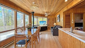 A wooden interior with a dining area, sofa, and kitchenette.