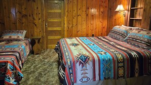 Una habitación de madera con dos camas, cada una con ropa de cama estampada.