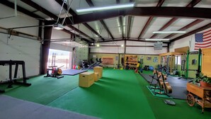 Un gimnasio con suelo verde, equipo de levantamiento de pesas y una bandera estadounidense.