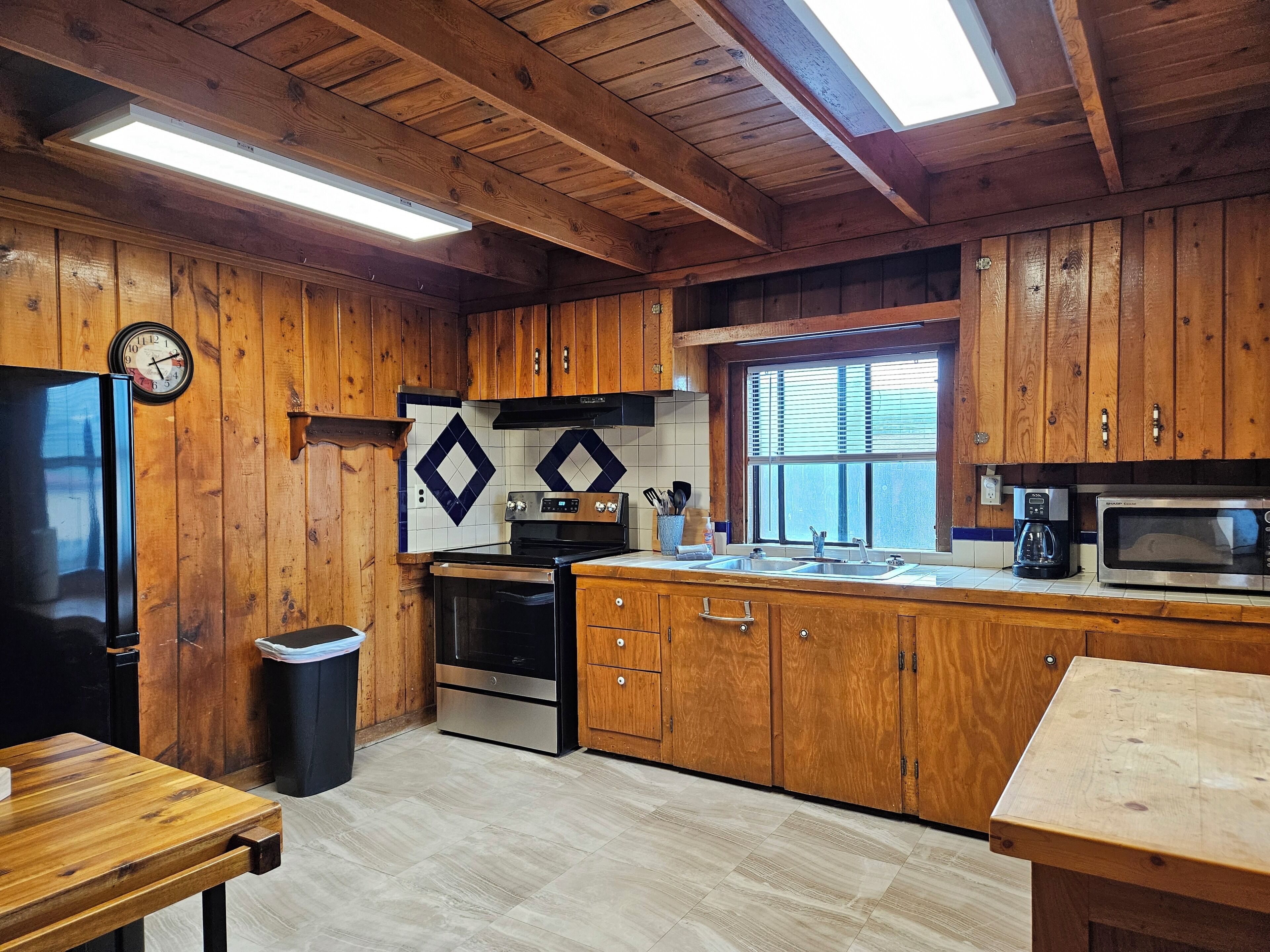 A kitchen with wooden cabinets, a stainless steel refrigerator, a microwave, and a coffee maker.