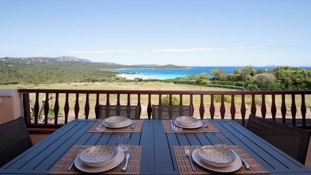 A table set for two with a view of the ocean and hills. - Harenae Beach Gateway by Wonderful Italy (Olbia)
