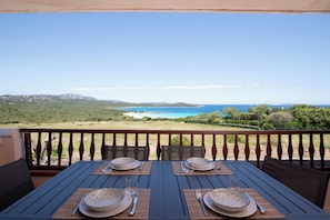 A table set for two with a view of the ocean and hills. - Harenae Beach Gateway by Wonderful Italy (Olbia)