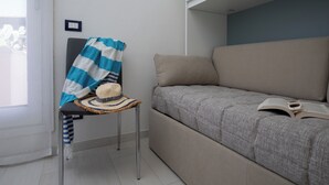 A room with a bed, a chair, a hat, and a book. - Harenae Beach Gateway by Wonderful Italy (Olbia)