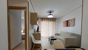 A compact living space with a kitchenette, a sofa, a dining table, and a chair.