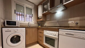 A compact kitchen with a washing machine, microwave, oven, and dishwasher.