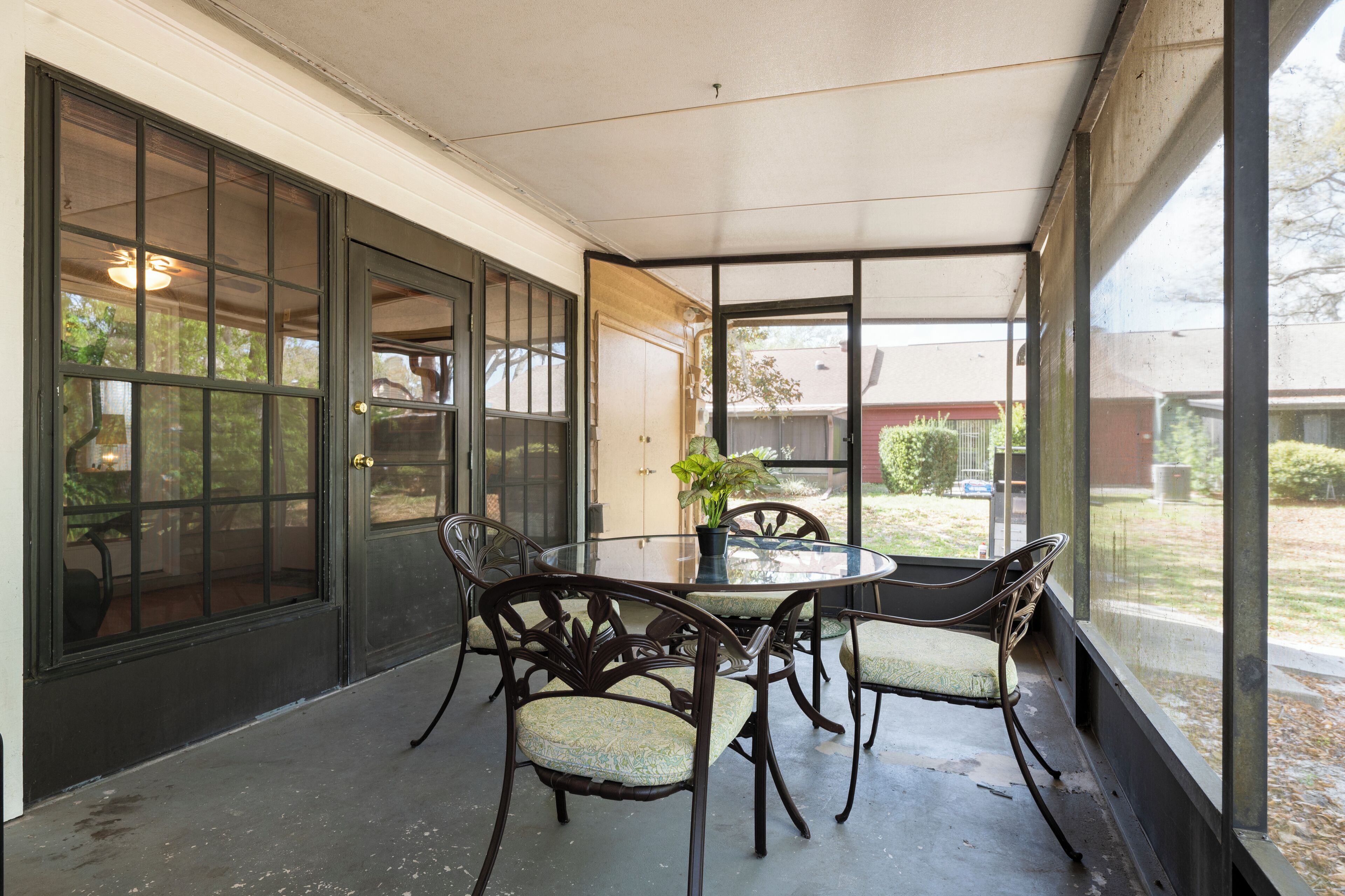 Un patio couvert avec une porte vitrée, une table ronde et quatre chaises.