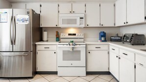 A modern kitchen with stainless steel appliances, white cabinetry, and a built-in microwave. - New King Bed in spacious Ridge Manor Villa with BBQ, Screened Lanai, and Views (Ridge Manor)