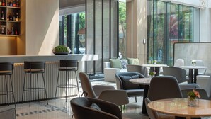 A modern bar area with stools, a seating area with round tables and chairs, and large windows offering a view of the outdoors. - Seaview Gleetour Hotel Shenzhen (Shenzhen)
