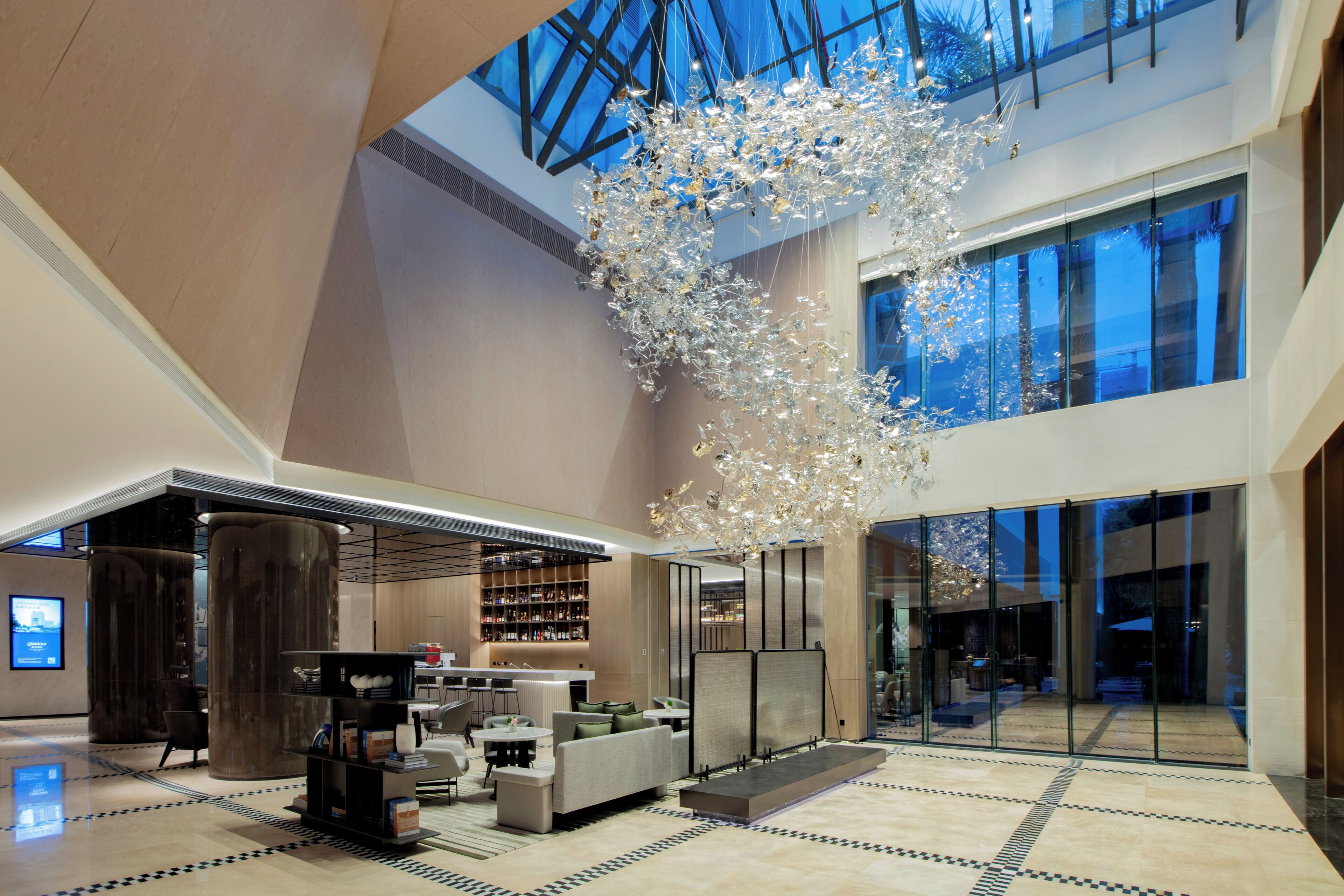 A spacious lobby with a high ceiling, a large chandelier, and a seating area with sofas and a coffee table.
