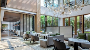 A modern hotel lobby with a mix of seating areas, including sofas and chairs, a central round table, and a decorative chandelier. - Seaview Gleetour Hotel Shenzhen (Shenzhen)