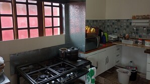 A kitchen with a gas stove, a microwave, and a sink. There is a window with a view of the outside, and a tiled backsplash. - Casa da Dine (Campos do Jordão)