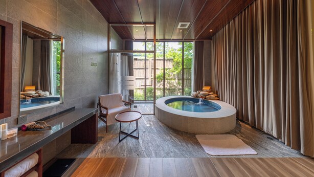 A modern bathroom with a bathtub, a seating area, and a large window. - Hyakumangoku Onsen Hotel - Free Shuttle Service to Shanghai Disneyland (Shanghai)