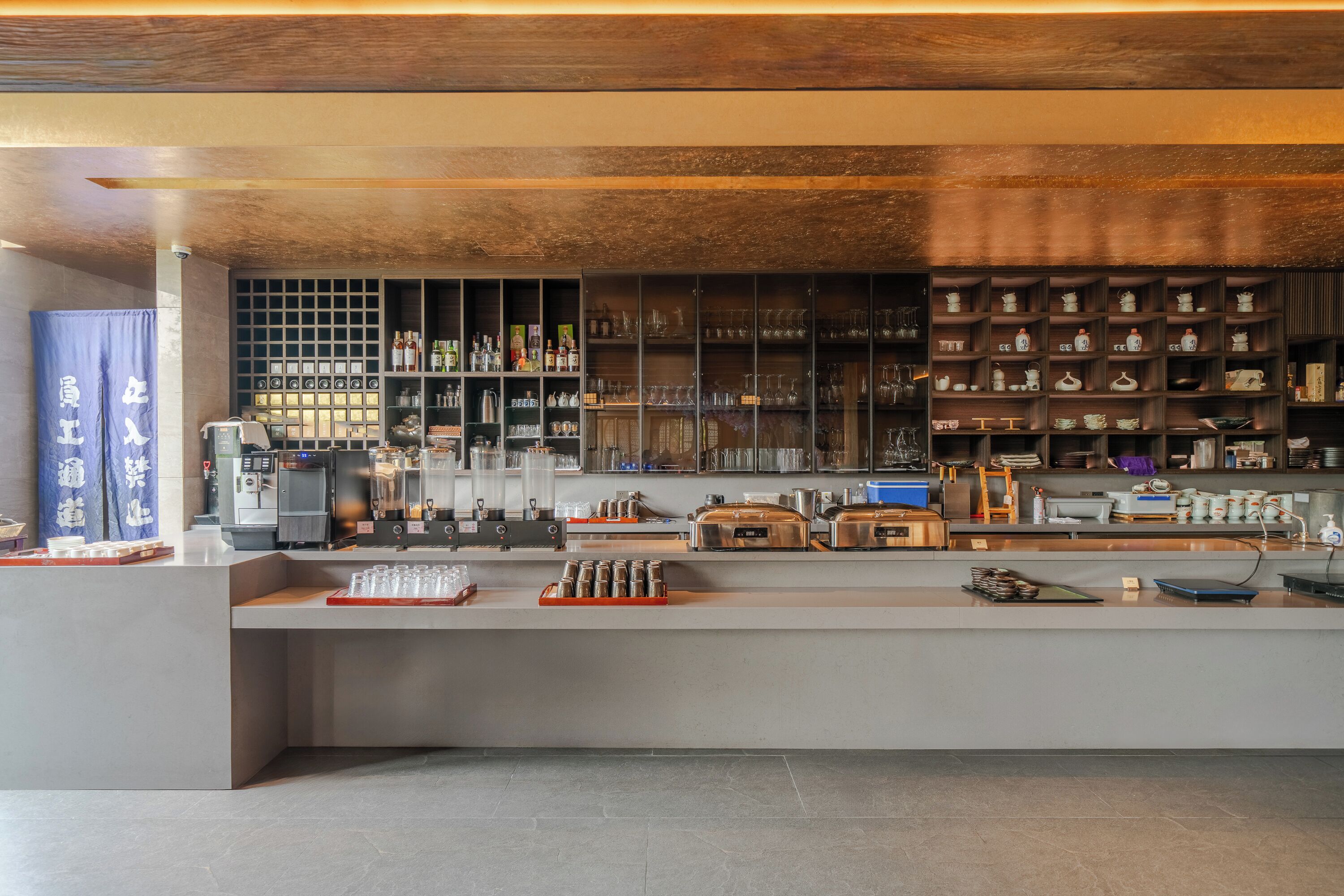 Eine Bar mit Regalen voller Flaschen und Gläsern, einer Kaffeemaschine und einer Theke mit verschiedenen Gegenständen.
