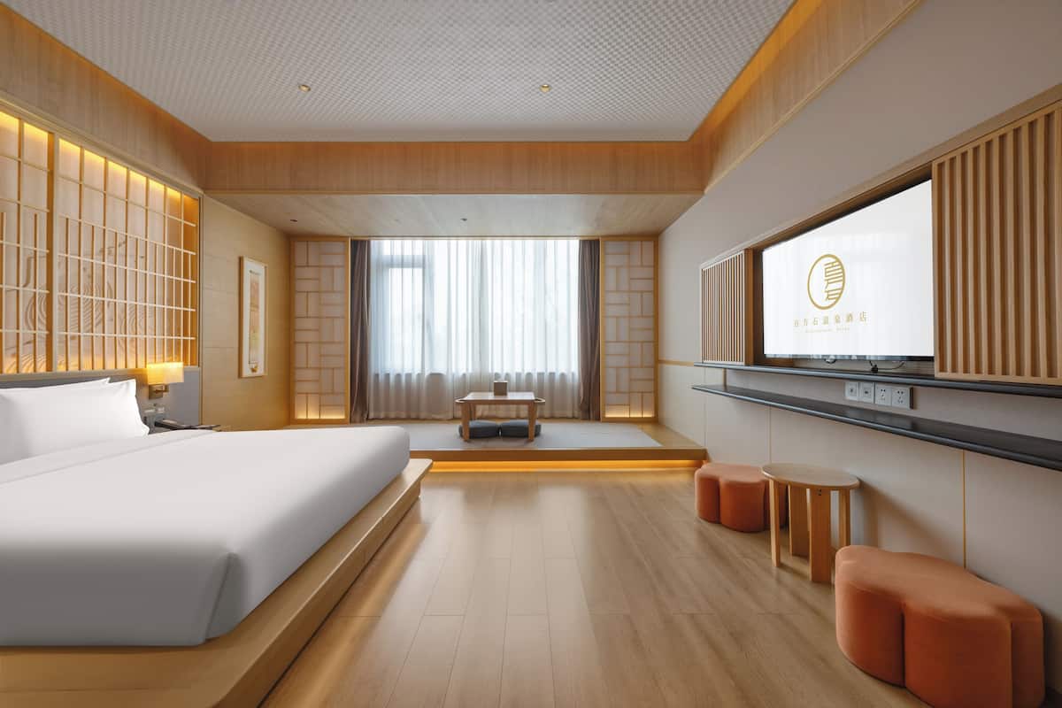 Une chambre d’hôtel moderne équipée d’un grand lit, d’un bureau et d’une télévision.