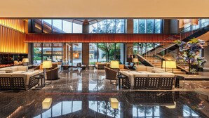 A spacious lobby with a high ceiling, a central seating area with sofas and armchairs, a staircase, and a large window offering a view of the outdoors. - Hyakumangoku Onsen Hotel - Free Shuttle Service to Shanghai Disneyland (Shanghai)