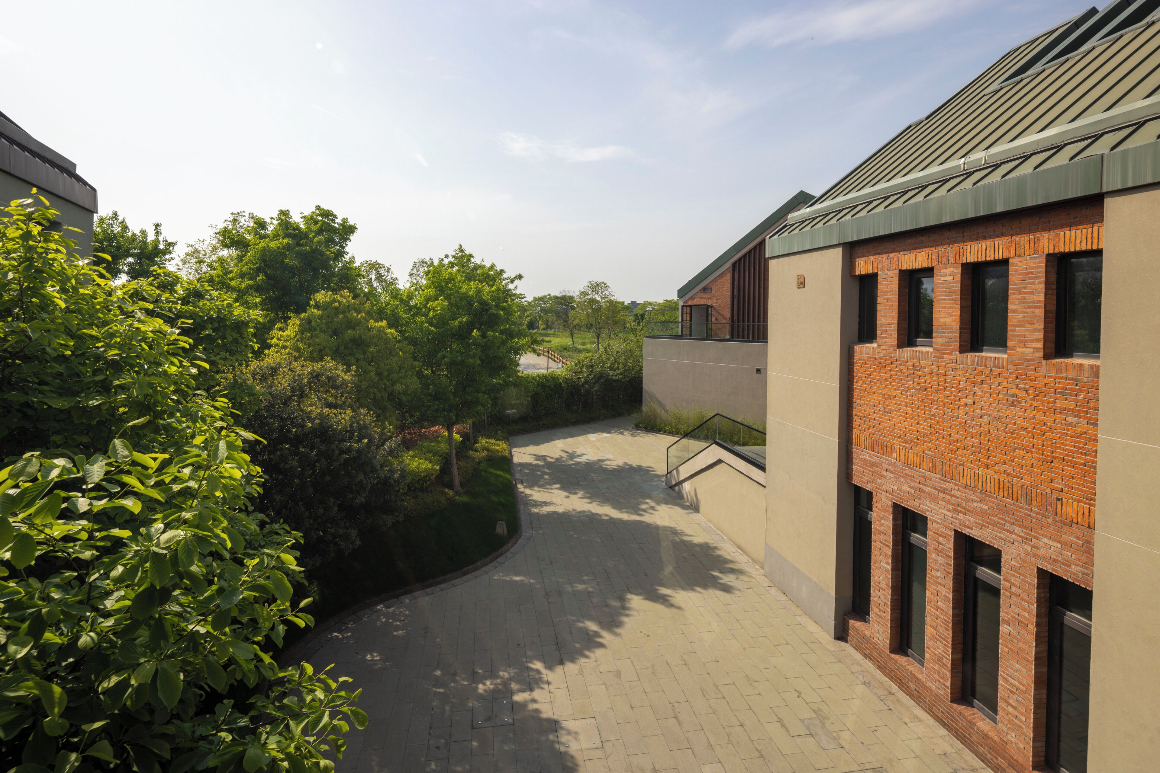 A pathway leading to a building with a brick facade and large windows.