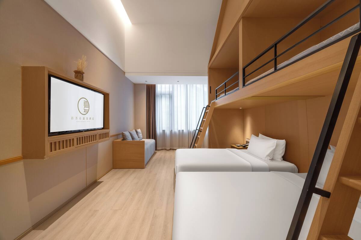 Une chambre d’hôtel avec un lit, un bureau, une télévision, une fenêtre avec des rideaux et un escalier.