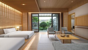 A modern hotel room with a wooden ceiling, large sliding glass doors leading to a garden, a sofa, two chairs, and a small table. - Hyakumangoku Onsen Hotel - Free Shuttle Service to Shanghai Disneyland (Shanghai)