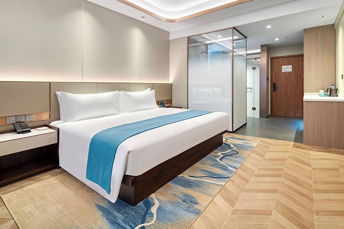 Una camera d'albergo moderna con un letto grande, un comodino con il telefono e un tavolino.