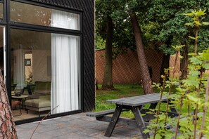 A modern house with a sliding glass door, a patio with a table, and a fenced backyard. - Lodge in Schaijk With Private Sauna (Schaijk)
