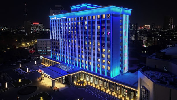 A multi-story hotel with a modern design, featuring a prominent entrance and a parking area. - Chang baishan Hotel (Changchun)