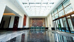 A spacious lobby with a high ceiling, large windows, and a reflective marble floor. - Chang baishan Hotel (Changchun)