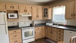 A kitchen with wooden cabinets, a white stove, a microwave, and a dishwasher. - Central PEI location minutes to golf and beaches.  (Cornwall)