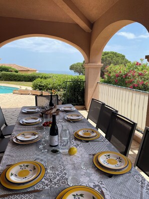 An outdoor dining area with a table set for four, overlooking a pool and garden.