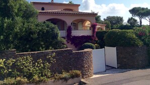 Ein Haus im mediterranen Stil mit einer Steinmauer, Bogenfenstern und einem weißen Tor.
