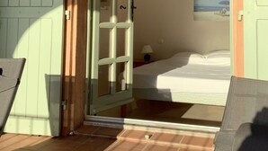 Ein Zimmer mit einem Bett, einem Strandbild und einer Tür zu einem anderen Raum.