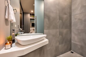 Ein modernes Badezimmer mit einem großen weißen Waschbecken, einem Spiegel und einer Duschkabine.