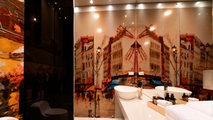 Ein modernes Badezimmer mit einem großen Spiegel, einem weißen Waschbecken und einem schwarzen Stuhl.