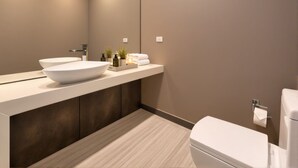 Ein modernes Badezimmer mit einem großen, weißen Waschbecken, einem Spiegel und einer Toilette.
