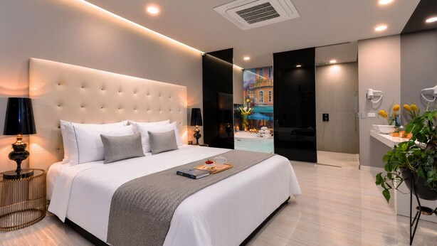 Ein modernes Hotelzimmer mit einem großen Bett, Nachttischlampen, Blick auf den Pool und einem Badezimmer mit Waschbecken und Spiegel.