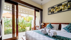 Habitación de hotel con una cama grande, vista a un jardín y un cuadro en la pared.