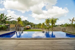 Una piscina al aire libre, sombrillas, sillones reclinables de piscina