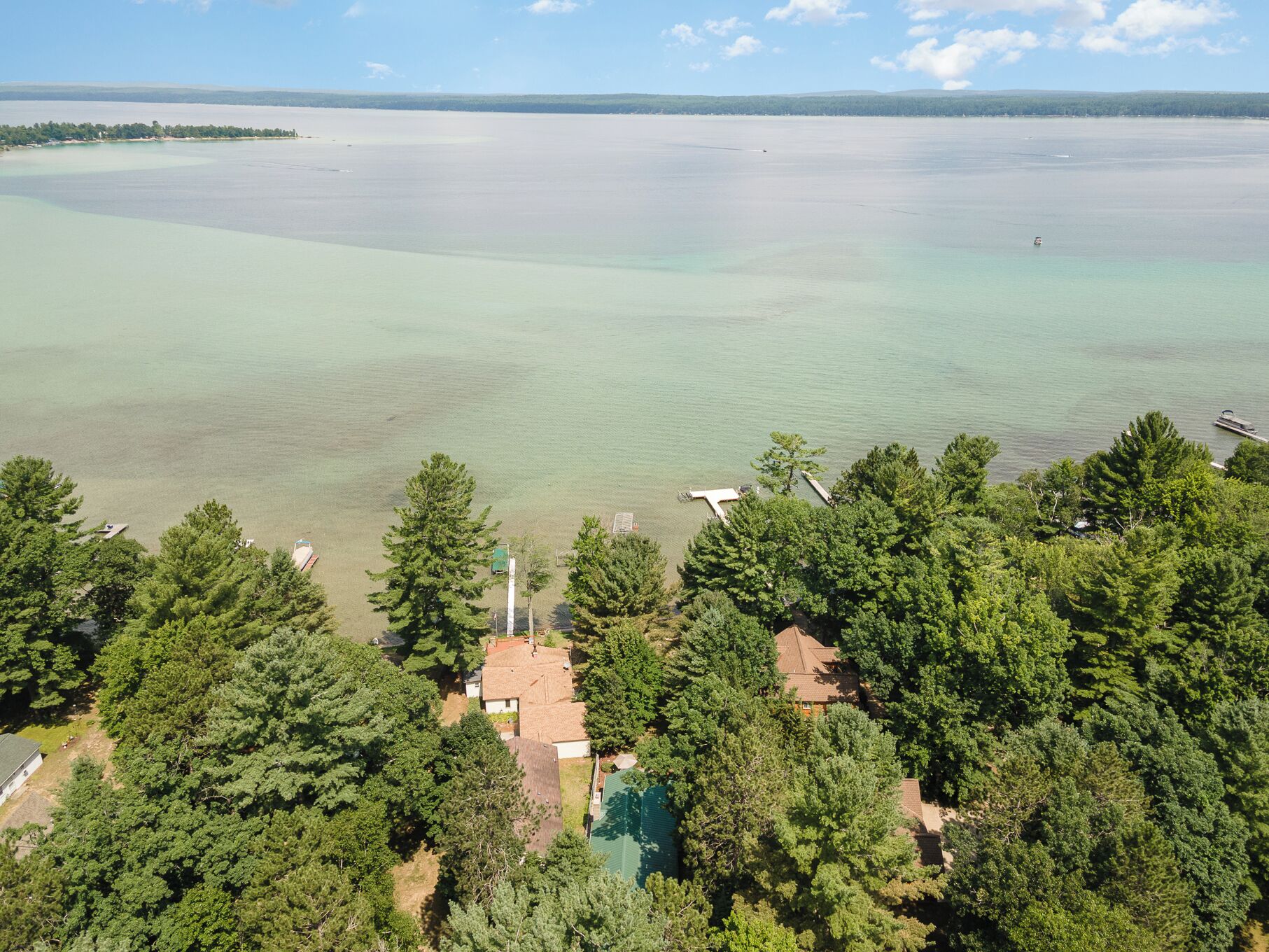 Une propriété située sur la côte, dotée d’une piscine et entourée d’une forêt dense, avec vue sur une vaste étendue d’eau.