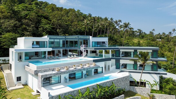 A modern multi-story house with a large swimming pool, multiple balconies, and lush greenery surrounding the property. - Villa Murano 9BR with Panoramic Sea View (Koh Samui)