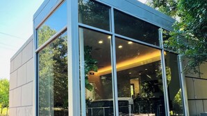 A modern building with large windows, stone base, and a view of the interior. - Private luxury — Minutes from City Center & airport (Austin)