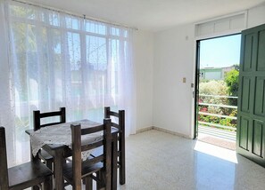 A room with a dining table and chairs, a window with sheer curtains, and a door leading outside. - Furnished upstairs apartment ideally located in Oaxaca's Historical District (Oaxaca de Juárez)