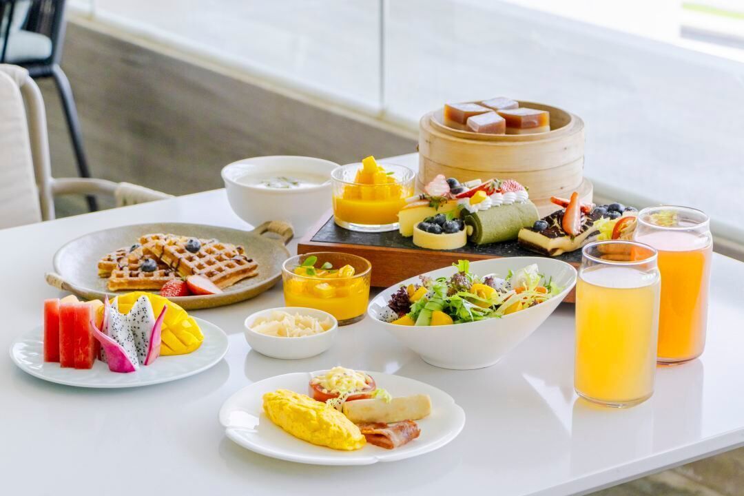 Un bufé de desayuno con diversos platos, como gofres, huevos y fruta.