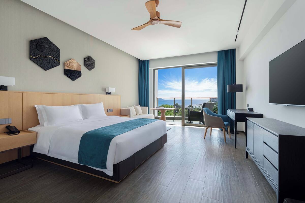 Een moderne hotelkamer met een groot bed, een bureau en een televisie.