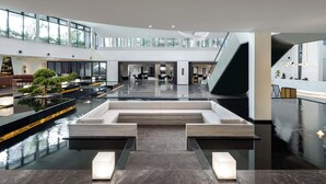A spacious lobby with a central seating area, a staircase, and a reception desk.