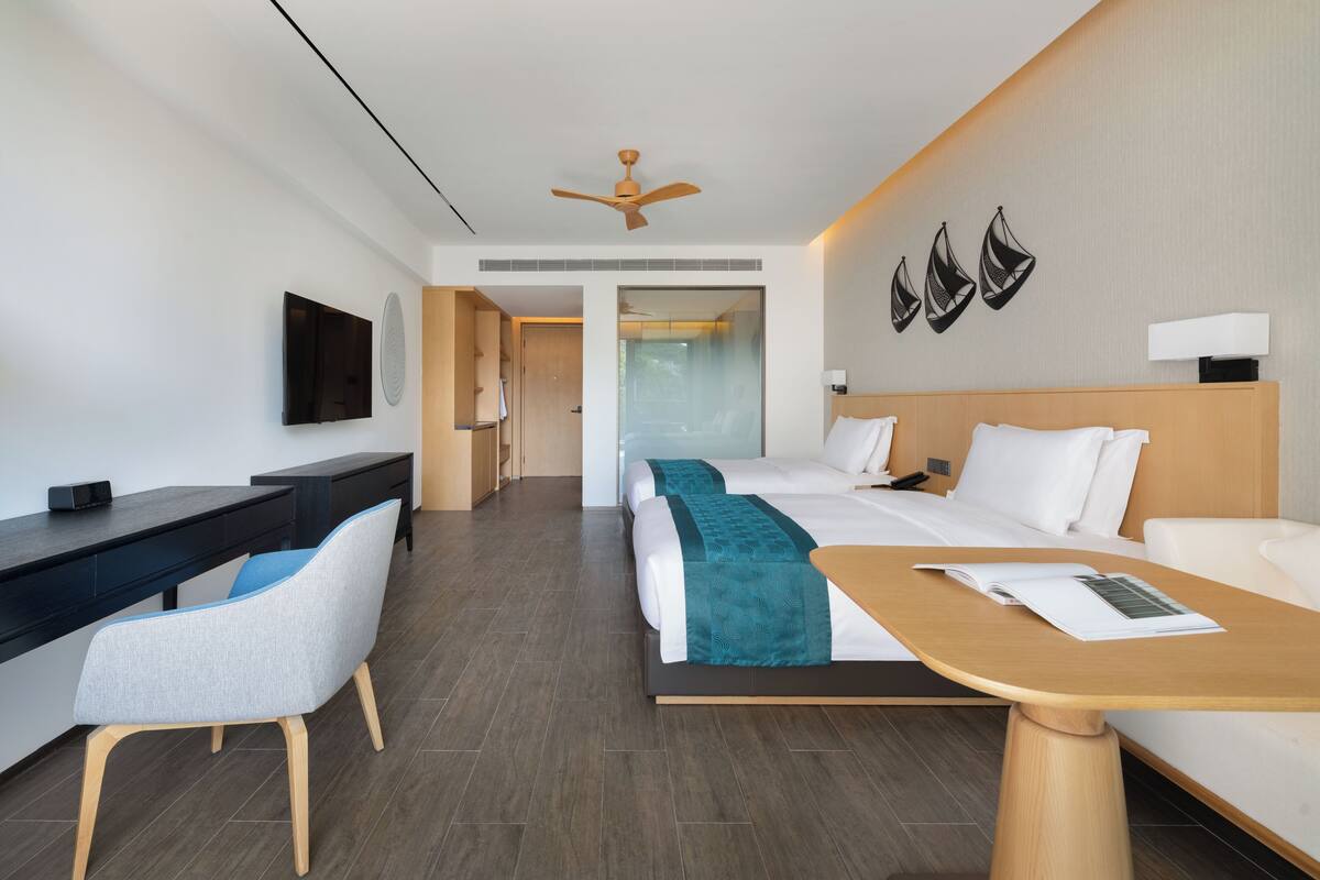Een moderne hotelkamer met een bed, bureau, stoel en plafondventilator.