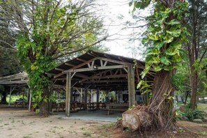 A covered picnic area with benches and tables, surrounded by trees. - Ara Dinawan Island Resort (Kinarut)
