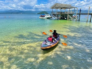 A kayak on clear water with a dock and boat in the background. - Ara Dinawan Island (Kinarut)