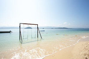 A beach with clear water, a swing set, and distant mountains. - Ara Dinawan Island (Kinarut)
